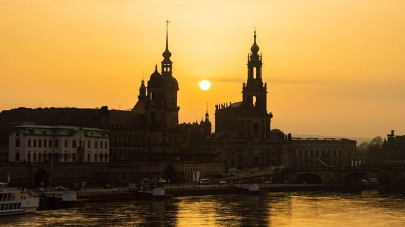 Die Sonnenscheibe, durch den Saharastaub, besonders orange eingefäbt, geht hinter der Silhouette der Dresdner Altstadt unter.