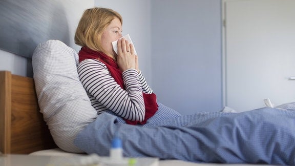 Frau liegt krank im Bett