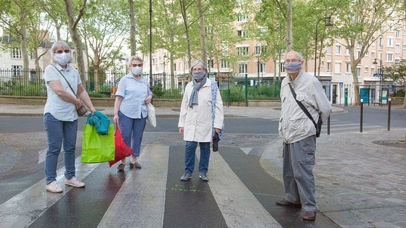 Gruppe von Senioren auf Spaziergang in Paris mit Mundschutz.