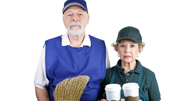 Ein älterer Mann mit einem Besen, eine ältere Frau mit Kaffeebechern