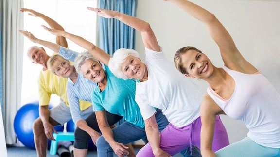 Junge Trainerin mit Senioren-Sportgruppe beim Yoga