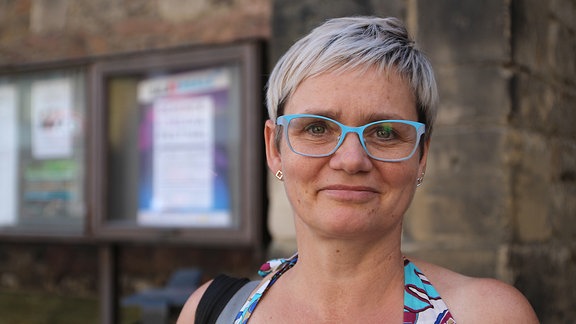 Porträtaufnahme einer Festivalbesucherin mit kurzen blonden Haaren und türkiser Brille