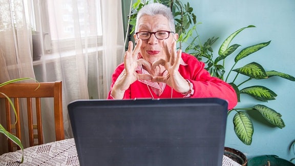 Eine ältere Frau sitzt vor einem Laptop.