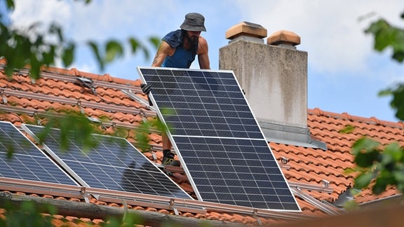Solarmodule werden auf ein Hausdach transportiert. 