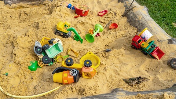 Sandkiste mit verschiedenen Spielzeugen aus Kunststoff