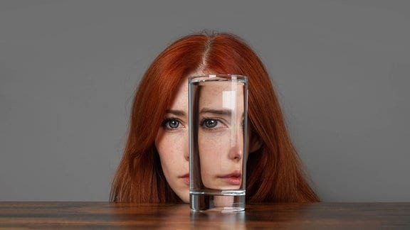 Eine Frau hinter einem Wasserglas