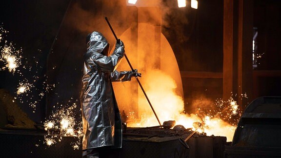Ein Stahlarbeiter entnimmt eine Probe am Abstich des Hochofens