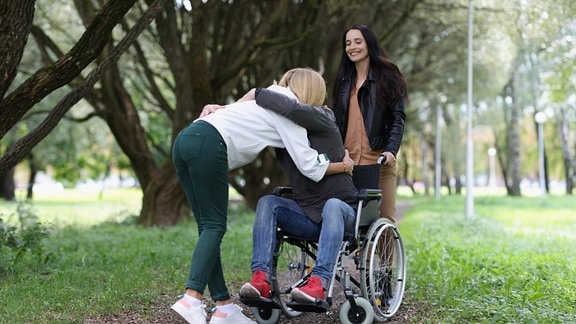 Eine Person umarmt eine andere Person im Rollstuhl.