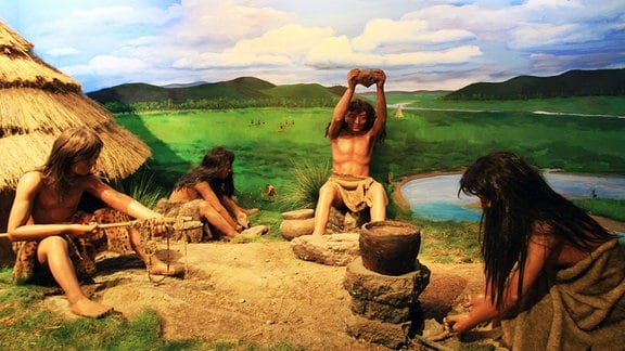 Ein Bild zeigt Steinzeitmenschen bei der Arbeit.