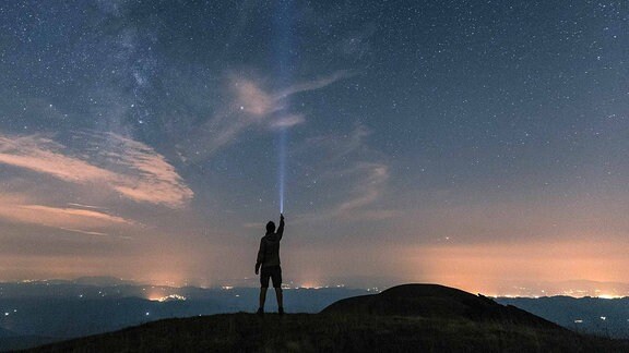 Ein Mann auf dem Gipfel eines Berges unter dem Sternenhimmel