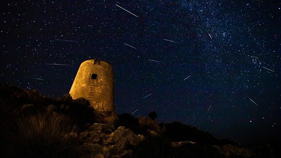 Perseiden-Meteoritenschauer und Milchstraße und mittelalterlicher Turm im Vordergrund 