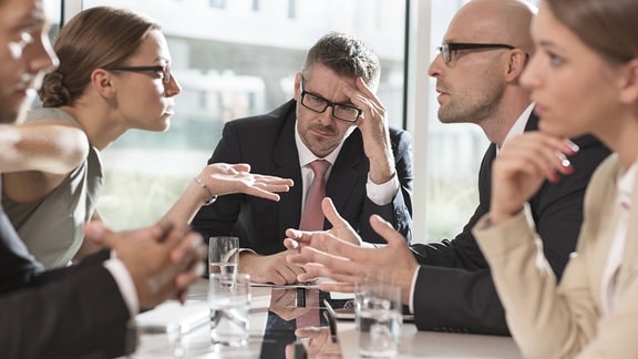 Fünf Geschäftsleute im Streit am Tisch