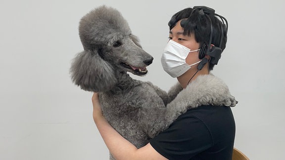 Ein Proband der südkoreanischen Studie spielt mit einem Hund. Währenddessen werden seine Hirnströme per EEG aufgezeichnet.