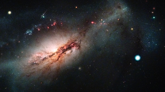 Bild von einer Galaxie, rechts daneben ein heller weißer Punkt, der einen in einer Supernova explodierenden Stern zeigt.