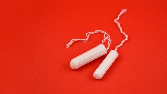 Tampons liegen auf einem roten Untergrund.