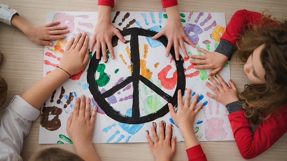 Eine Gruppe Kinder malt ein Bild mit dem Friedenssymbol