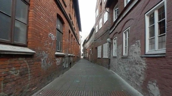 Kleine Straße mit flachen Häuserfassaden aus Backstein links und rechts