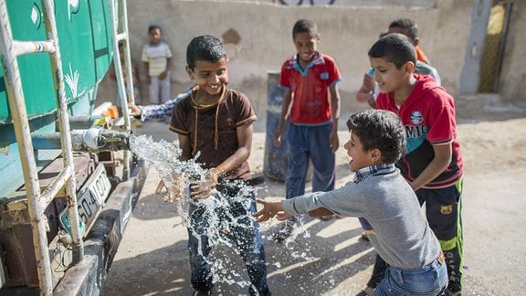 Jordanische Kinder spielen an einem Wassertanker