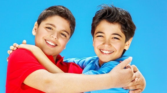 Zwei Jungen lächeln arm in Arm.