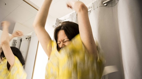 Eine Frau probiert ein Sommerkleid in einer Umkleidekabine an