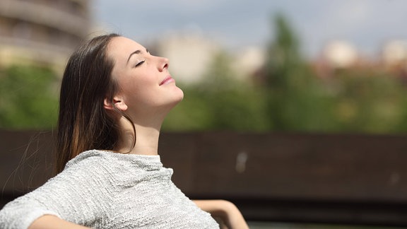 Urbane Frau atmet tief frische Luft