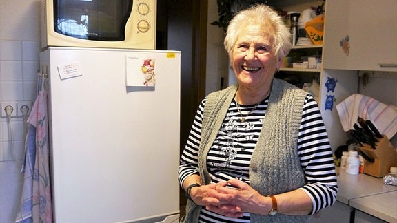 Frau, neben einem Kühlschrank stehend
