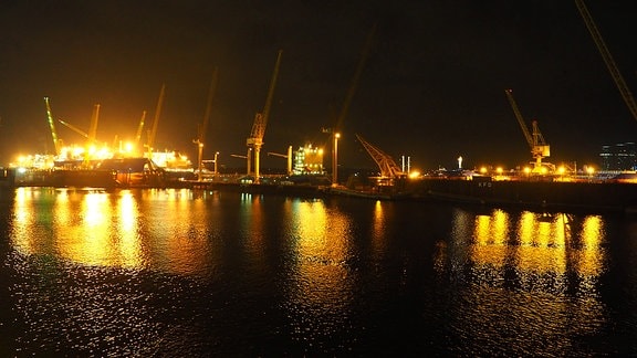 Nachtaufnahme von hell erleuchteten Gebäuden im Hafen von Singapur vom Wasser aus gesehen