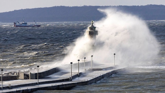 Bei einem Wintersturm  krachen meterhohe Wellen an den Leuchtturm in Sassnitz