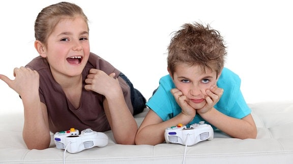 Lächelndes Mädchen und frustrierter Junge mit Gamecontrollern