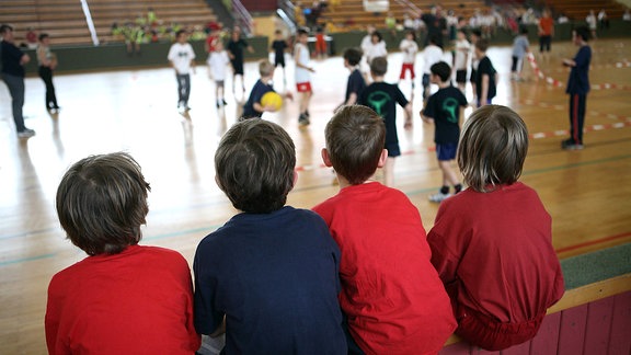 Kinder schauen beim Voelkerballspiel in einer Turnhalle zu