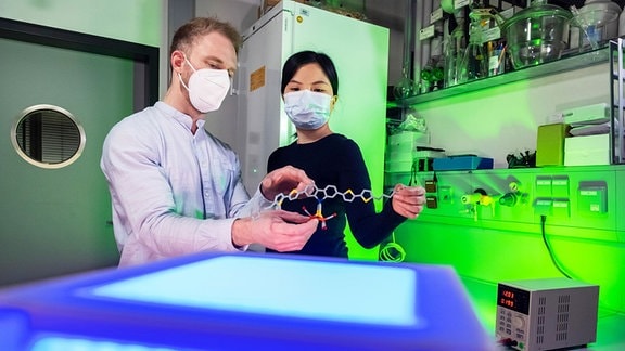 Eine Frau und ein Mann stehen in einem Labor vor technischen Geräten. 