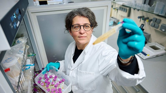 Eine Frau nimmt in einem Labor tiefgefrorene Urinproben aus einem Gefrierschrank