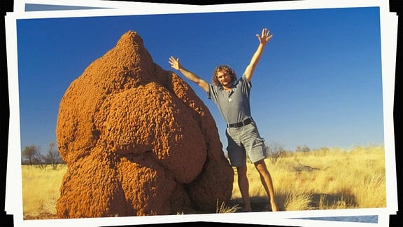 Ein junger Mann posiert neben einem roten Felsen