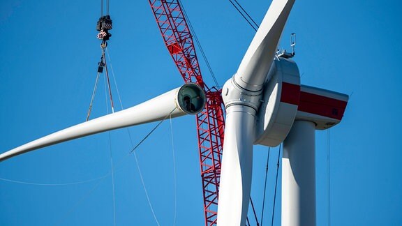 Montage einer Windenergieanlage, das letzte Rotorblatt wird montiert.