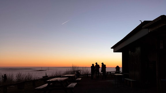 Silhouetten dreier Personen vor dem Hintergrund eines Sonnenuntergangs