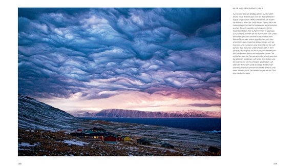 Das Bild zeigt im unteren Drittel eine karge Polarlandschaft mit dem grönländischen Dorf Qaanaaq. Darüber eine sehr dichte, düstere Wolkenformation, die an geraffte (dunkelblaue bis rosa) Textilien erinnert. 