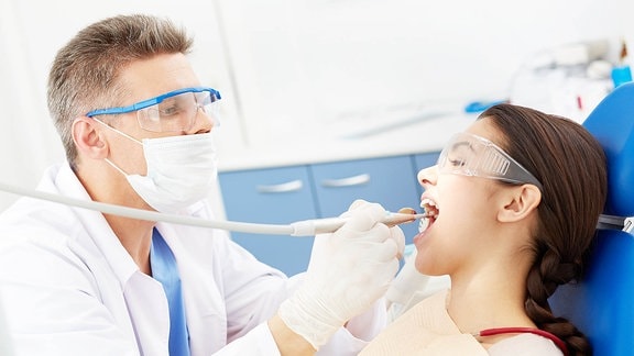 Ein Zahnarzt untersucht ein junges Mädchen.