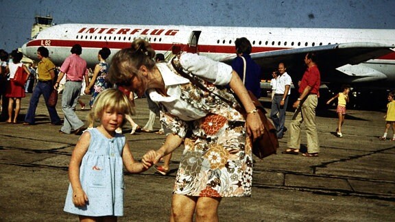 Frau und Kind vor Flugzeug