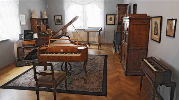 Ein historisch eingerichteter Raum mit einem Klavier und verschiedenen Schränken